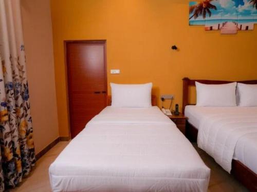 two beds in a room with orange walls at Infenta's Villa in Pandattarippu