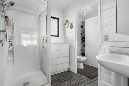 a white bathroom with a toilet and a sink at Arkhos - Whitianga Holiday Home in Whitianga