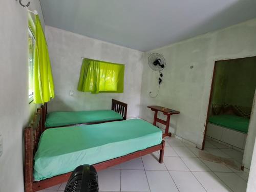 a bedroom with a bed with green sheets and a window at Casa Ariramba - Your place in COP30 in Belém
