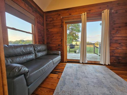 a living room with a leather couch and a large window at Modern Log House First Level Primary in Winchester