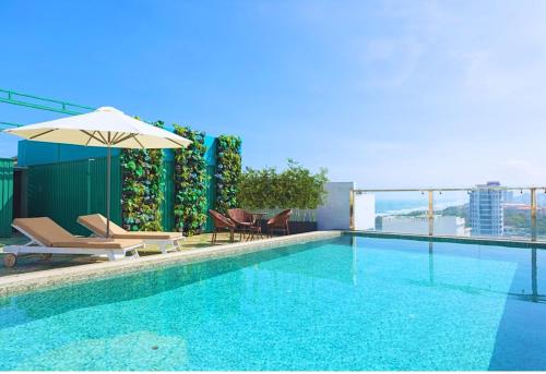een zwembad met ligstoelen en een parasol bij Palazzo Luxury Hotel & Bistro - Central My Khe Beach Walking Street in Da Nang