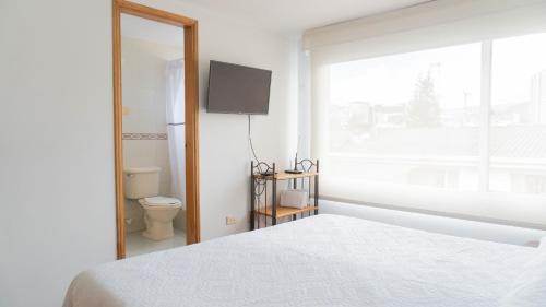 a bedroom with a bed and a window and a television at 100 Wonderful House in Bogotá