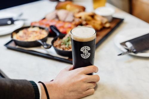 a person holding a glass of beer in front of food at Rydges Resort Hunter Valley in Lovedale