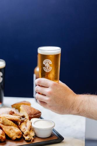 a man holding a glass of beer next to a plate of food at Rydges Resort Hunter Valley in Lovedale