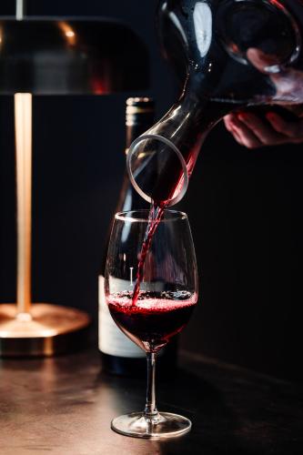 a person pouring red wine into a wine glass at Rydges Resort Hunter Valley in Lovedale
