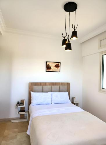 a bedroom with a large white bed with two lights at Signature Villa à la Plage in Temara