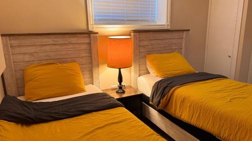 a bedroom with two beds with yellow pillows and a lamp at Calgary Super Cozy Guest Rooms Near Banff in Calgary