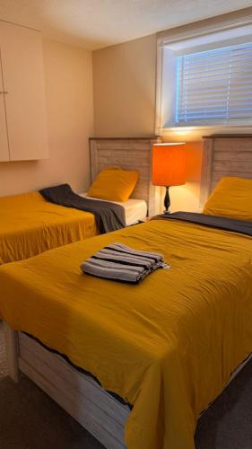a bedroom with two beds with yellow sheets and a window at Calgary Super Cozy Guest Rooms Near Banff in Calgary