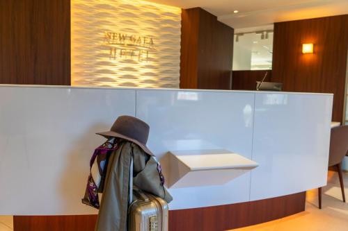 a hat and a suitcase in front of a counter at Hotel New Gaea Domemae in Fukuoka