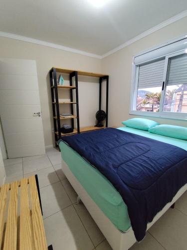 ein Schlafzimmer mit einem Bett mit blauen Laken und einem Fenster in der Unterkunft Rosario Apartamento in Santa Maria
