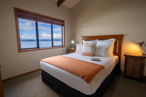 a bedroom with a large bed with a large window at Oreti Collection - By Vacations in Paradise in Turangi