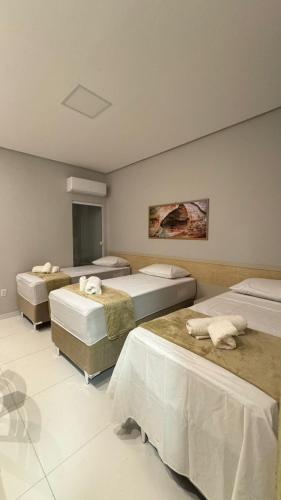 a bedroom with three beds in a room at Pousada Capivara Express in Baixas