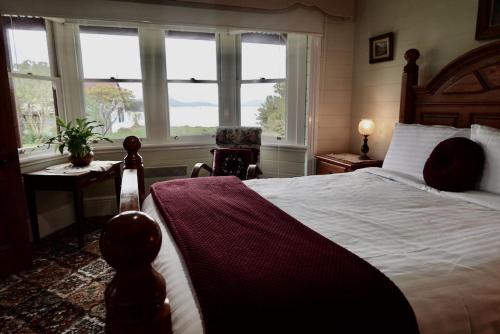 a bedroom with a large bed and windows at Waterfront Casilda Guesthouse in Dunalley