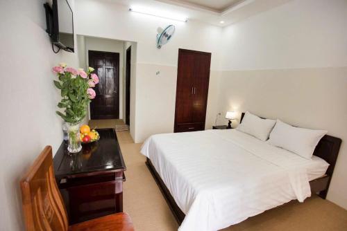 a bedroom with a bed and a vase of flowers on a table at Hyper Hotel in Buôn Ðũng