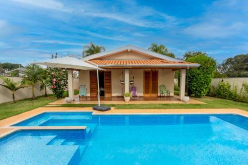 a villa with a swimming pool in front of a house at Piscina Aquecida Casa no Thermas de Sta Bárbara in Santa Bárbara do Rio Pardo