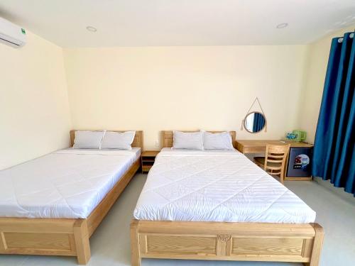 two beds in a room with blue curtains at Hoàng Hôn Nhớ Hotel in Ấp Khánh Phước (1)