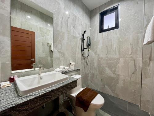 une salle de bain avec un lavabo, des toilettes et un miroir dans l'établissement Unchan Liveliness Pool Villa, à Ban Chong Phli