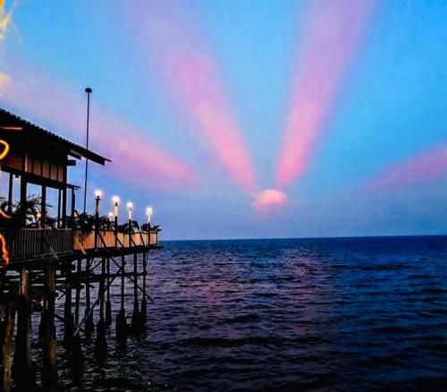 a pier with people sitting on it over the water at Karoon Sea View Lodge in Hua Hin