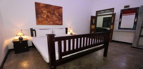 a bedroom with a bed and two lamps and a mirror at ayurvedamountainvilla in Nikawatawana