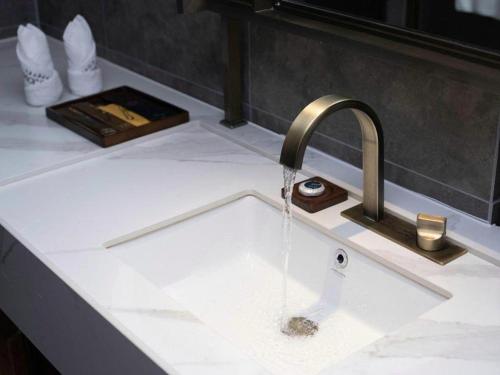 a kitchen sink with water pouring from a faucet at James Joyce Coffetel Kunming Railway Station Huancheng Nan Road Metro Station in Kunming