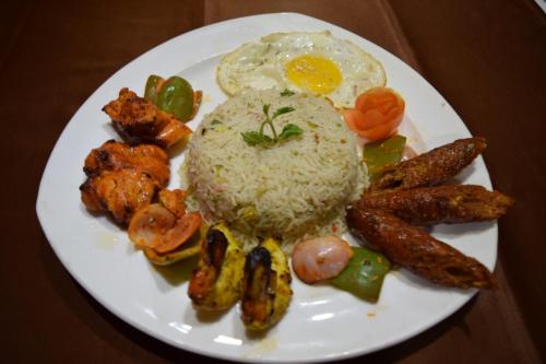 a plate of food with rice and fried eggs and mushrooms at Hotel The Sojourn in Kolkata