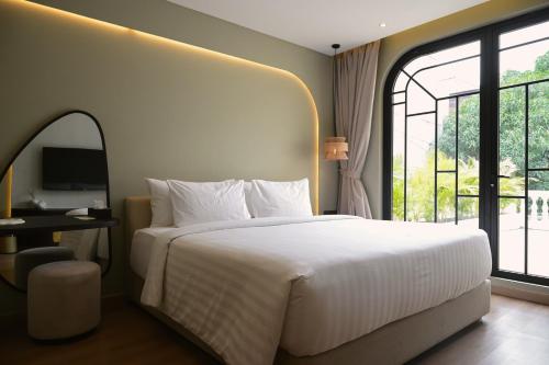 a bedroom with a large bed and a large window at Hygge Hotel and Villas Seminyak in Seminyak