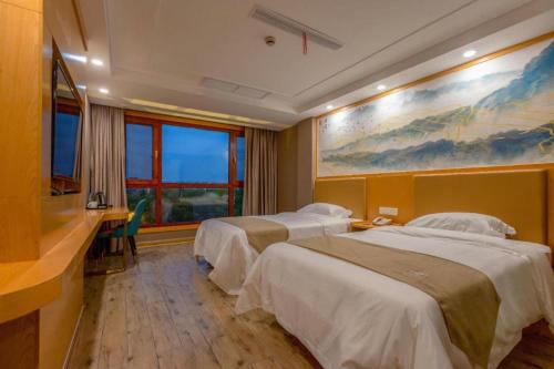 a hotel room with two beds and a painting on the wall at Shell Hotel Changzhou North Railway Station Global Harbor Metro Station in Changzhou