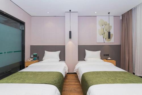 two beds in a hotel room with a tv at Green Tree Inn Express Fuzhou Three Lanes and Seven Alleys Nanmendou Metro Station in Fuzhou