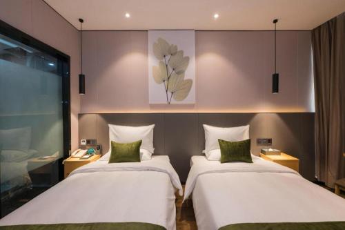 two beds in a hotel room with at Green Tree Inn Express Fuzhou Three Lanes and Seven Alleys Nanmendou Metro Station in Fuzhou