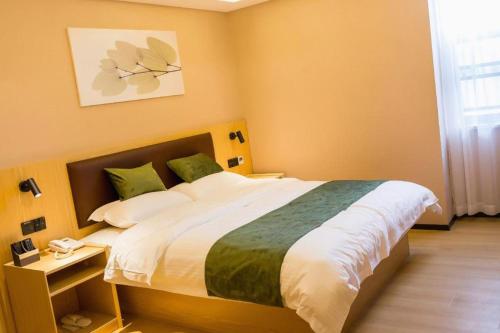 a bedroom with a large bed with yellow walls at GreenTree Inn Express Chuzhou Langya District Government Chuhe Road in Chuzhou