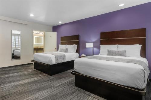 two beds in a hotel room with purple walls at SureStay Hotel by Best Western Beverly Hills West LA in Los Angeles