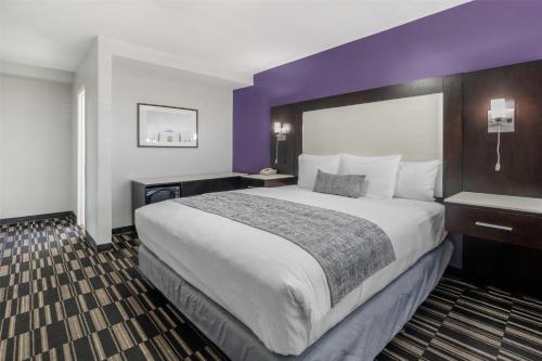 a hotel room with a large bed and purple walls at SureStay Hotel by Best Western Beverly Hills West LA in Los Angeles