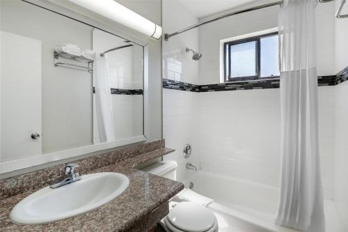 a bathroom with a sink and a toilet and a mirror at SureStay Hotel by Best Western Beverly Hills West LA in Los Angeles