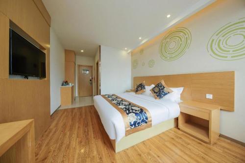 a hotel room with a bed and a flat screen tv at Green Tree Inn Fengxian New City Metro Station Jiukeshu Art Center in Shanghai