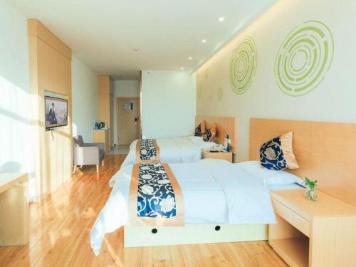 a large bedroom with two beds and a desk at Green Tree Inn Fengxian New City Metro Station Jiukeshu Art Center in Shanghai