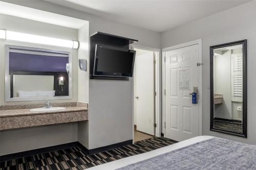 a hotel room with a bed and a sink and a tv at SureStay Hotel by Best Western Beverly Hills West LA in Los Angeles