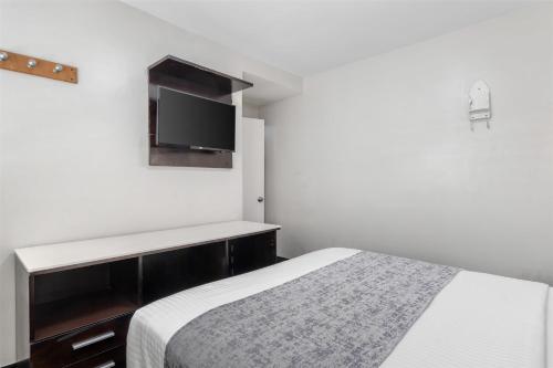 a bedroom with a bed and a tv on the wall at SureStay Hotel by Best Western Beverly Hills West LA in Los Angeles