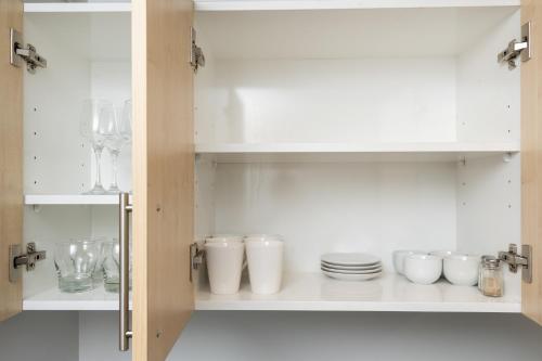 a cupboard filled with white dishes and plates at Grove Park Motor Lodge in Blenheim