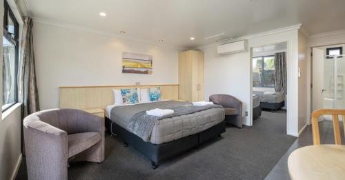 a bedroom with a bed and two chairs at Grove Park Motor Lodge in Blenheim
