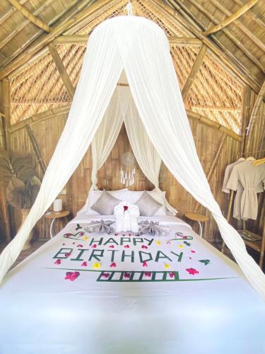 a bed in a tent with a happy birthday cake at Hidden Bamboo Village in Selat