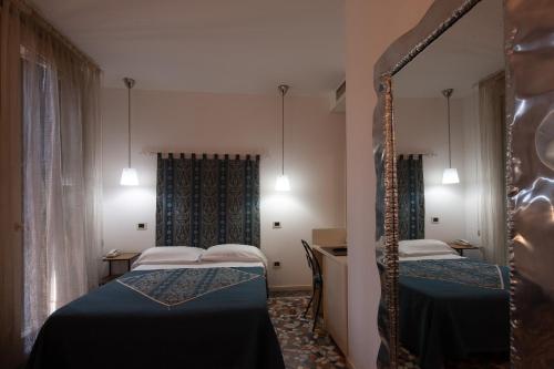 a room with two beds and a mirror at CityHotel Cristina Vicenza in Vicenza