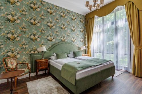 a bedroom with a green bed and floral wallpaper at Tilia Kúria in Bózsva