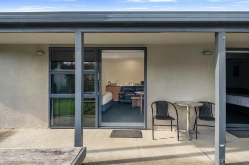 a patio with a table and chairs and a bedroom at Grove Park Motor Lodge in Blenheim