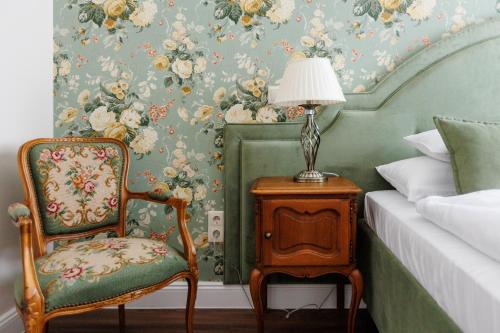 a bedroom with a chair and a table with a lamp at Tilia Kúria in Bózsva