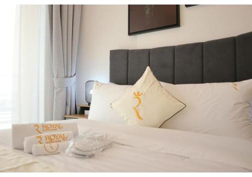 a bed with white sheets and pillows with a tray of food at Oasis 1BR Escape - Chic & Relaxing Apartment in Abu Dhabi