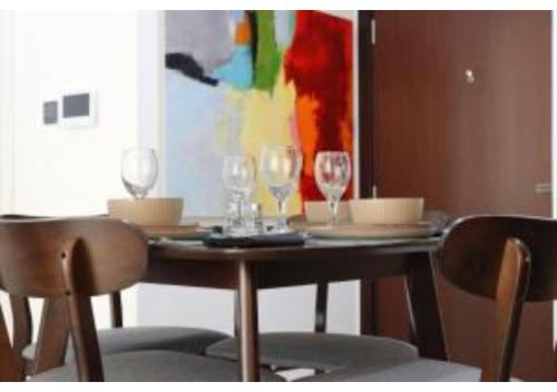a dining room table with two glasses and two chairs at Oasis 1BR Escape - Chic & Relaxing Apartment in Abu Dhabi