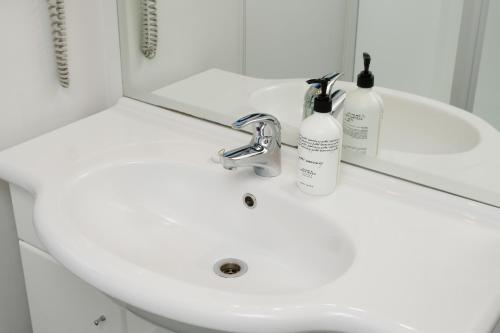 a white bathroom sink with two bottles on it at Grove Park Motor Lodge in Blenheim