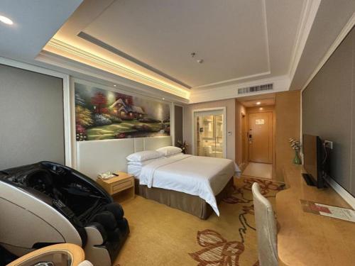 a bedroom with a bed and a painting on the wall at Vienna Hotel Guangdong Huiyang Qiuchang Yingbin Road in Huizhou