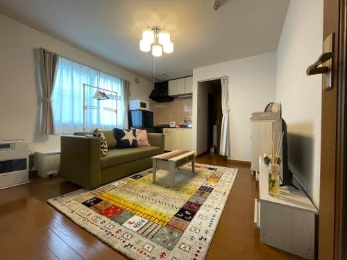 a living room with a couch and a table on a rug at クラージュ本郷通 in Sapporo