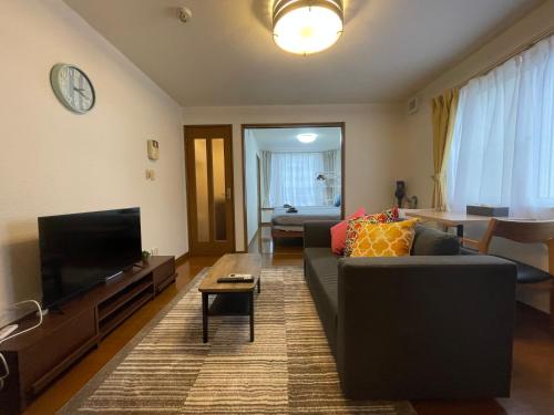 a living room with a couch and a flat screen tv at クラージュ本郷通 in Sapporo